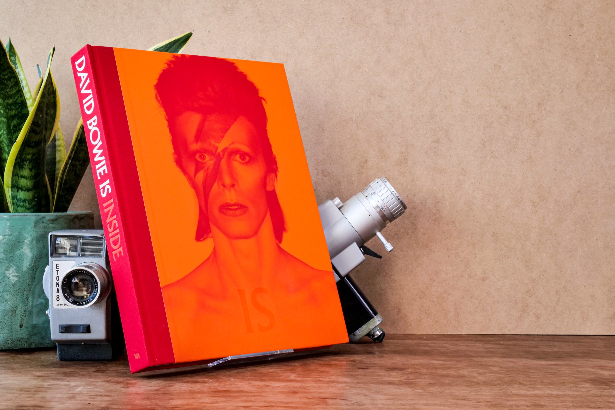 Wooden desk with book 'David Bowie Is' with an orange cover and image of Bowie.