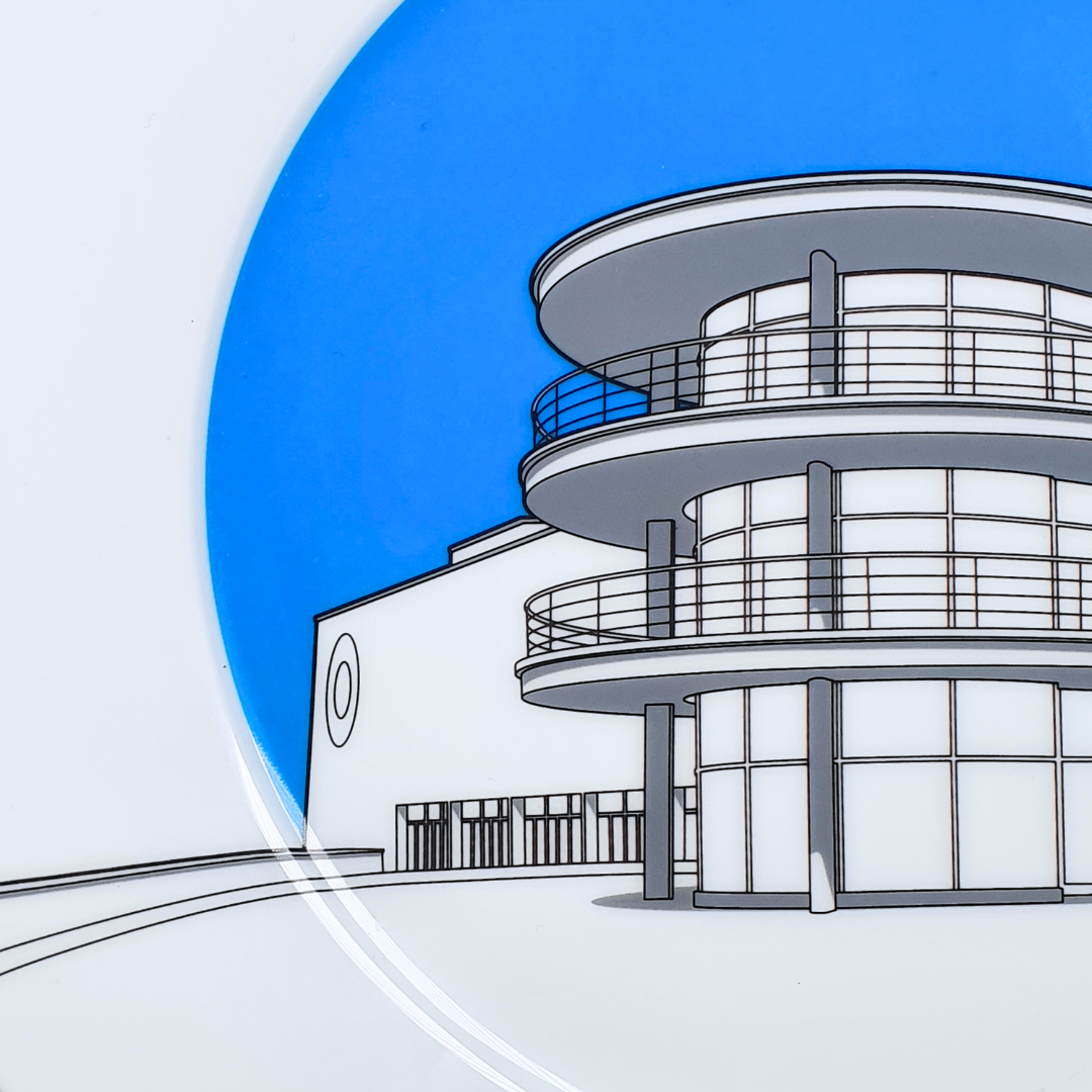 Close up of DLWP decorative white plate with a blue background and grey drawing of De La Warr Pavilion