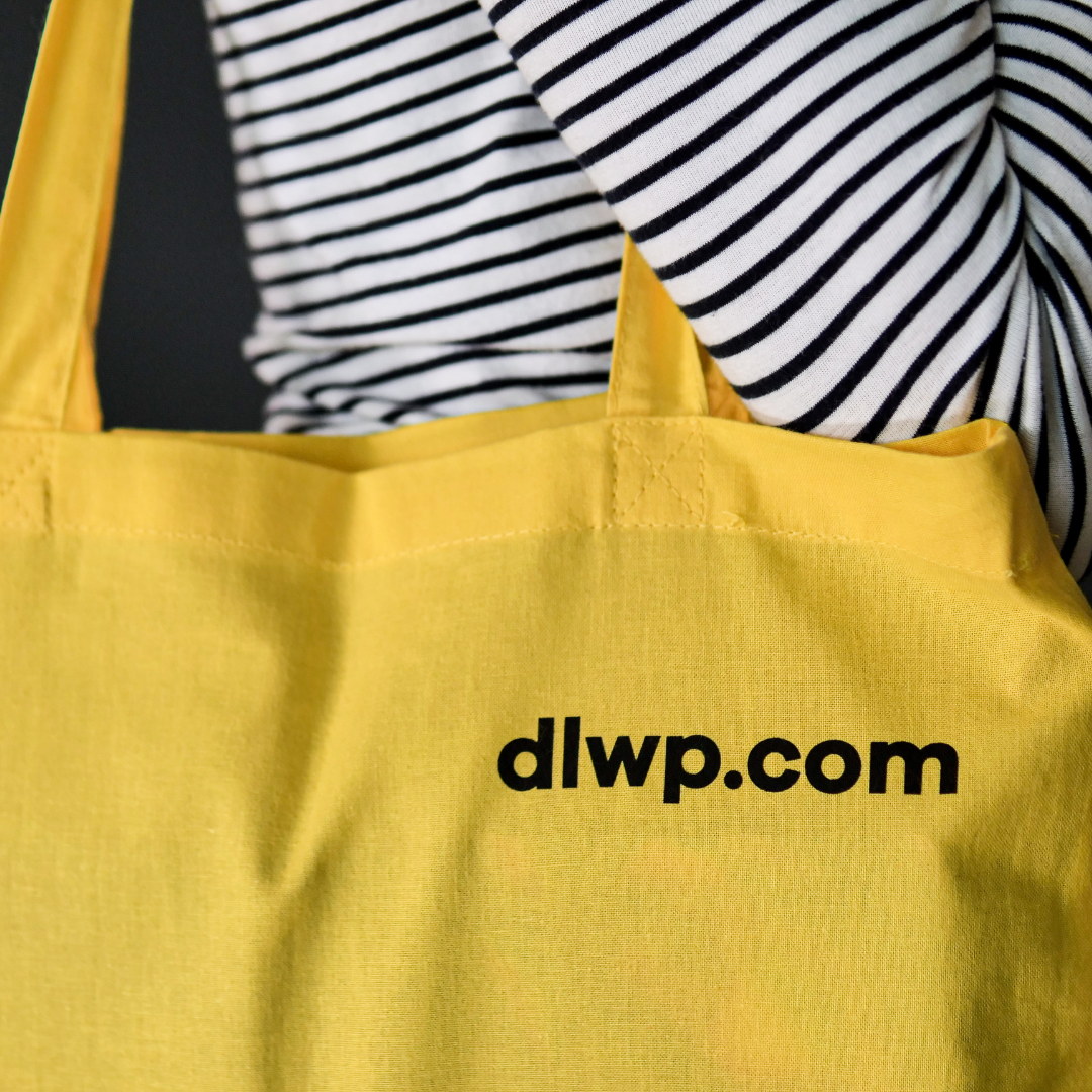 close up of bright yellow tote bag showing 'DLWP.com' in black