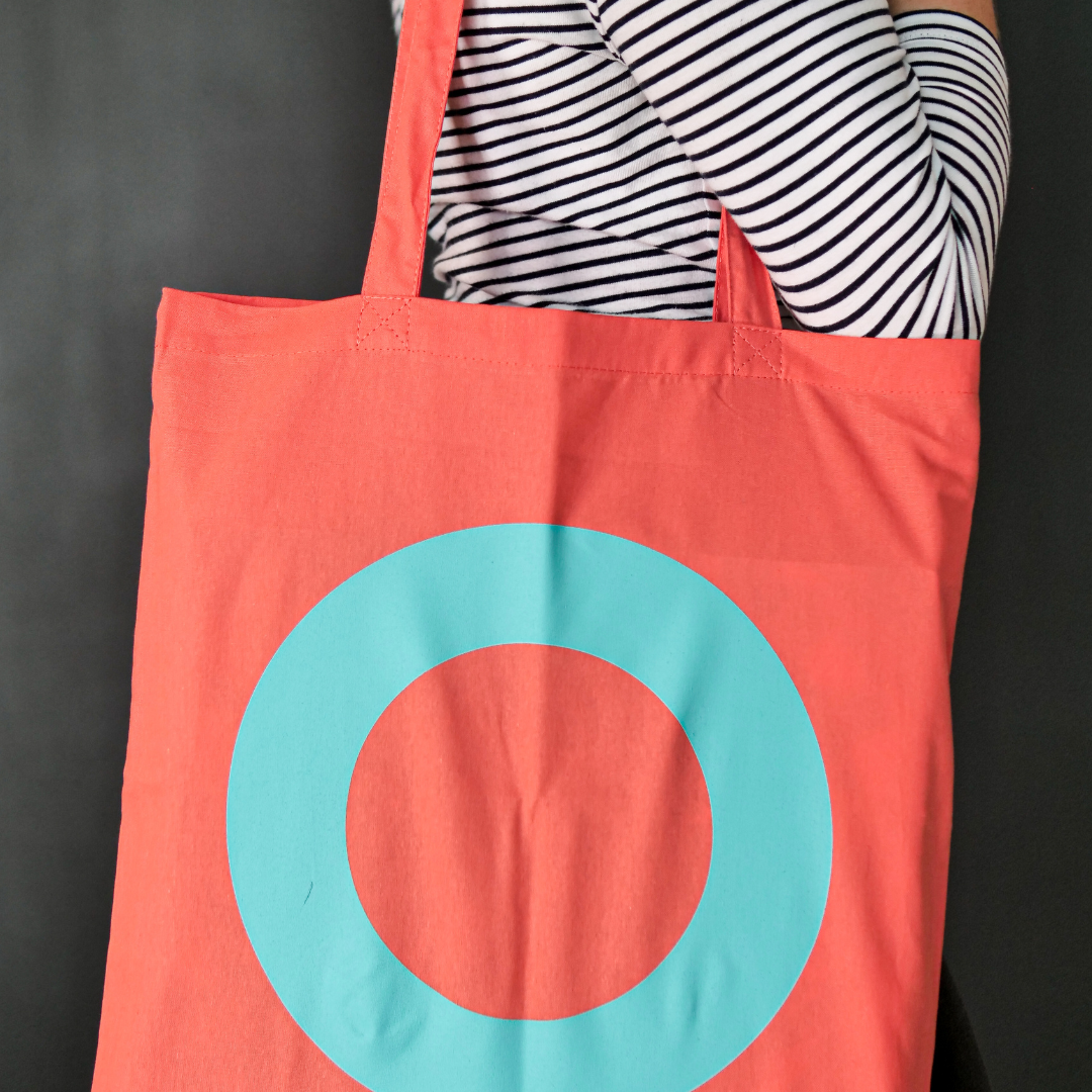 Bright coral canvas bag featuring the DLWP roundel in aqua blue