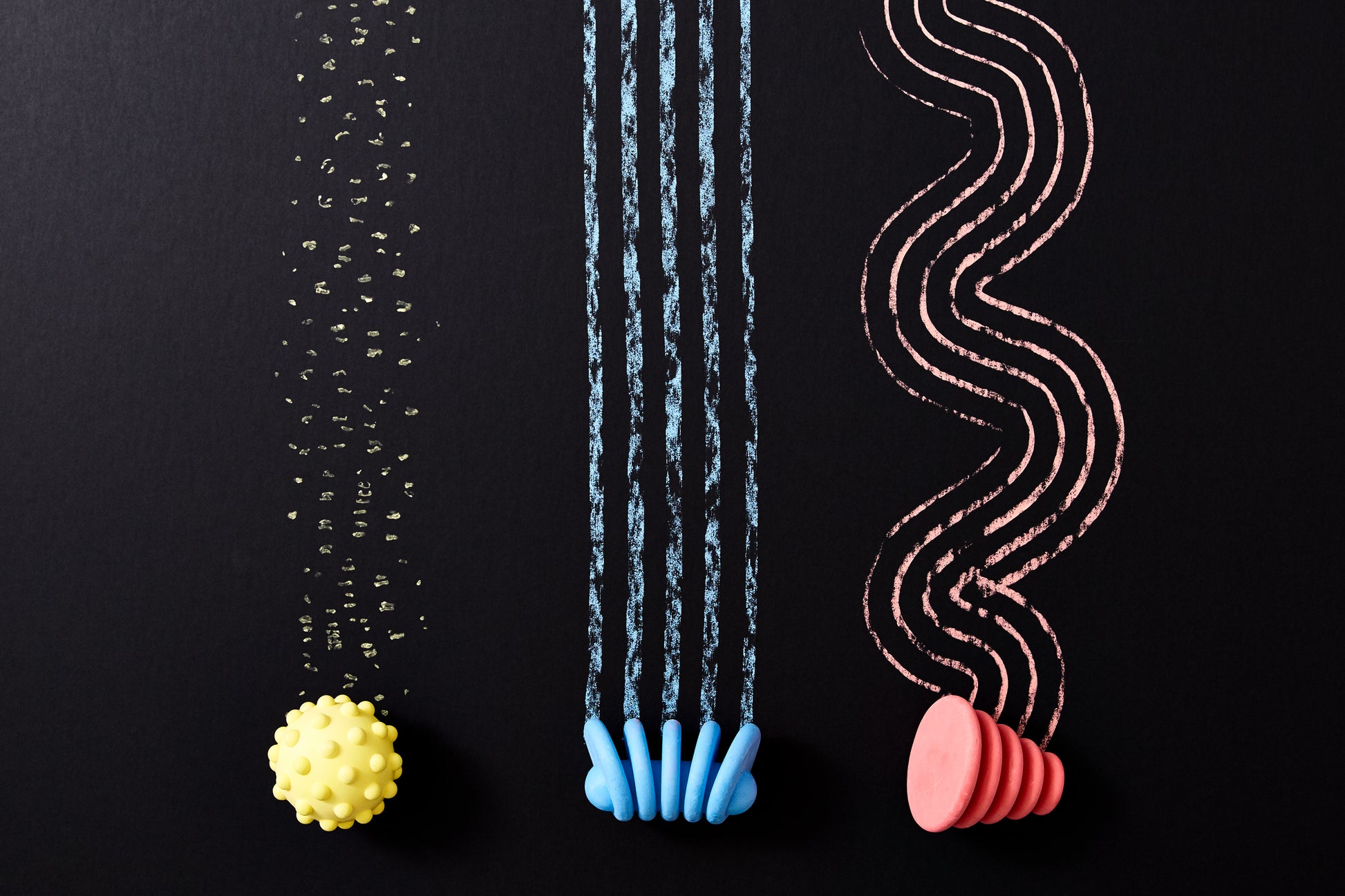 Red, blue and yellow chalks in various shapes being used on a black surface