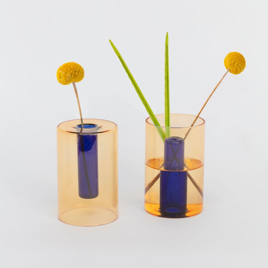 Two peach and cobalt reversible vases with yellow flower stems