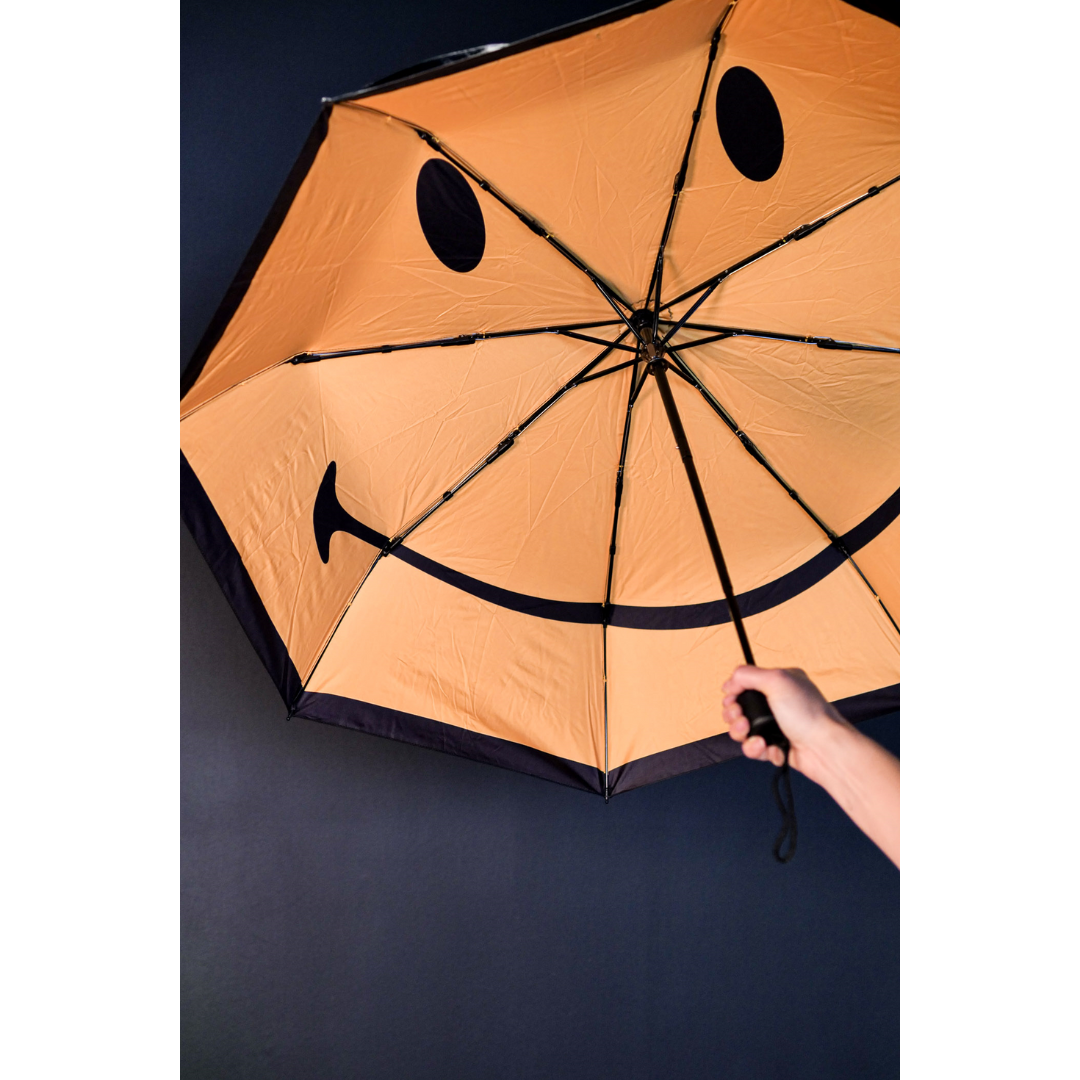 Open umbrella with a yellow Smiley Face inside