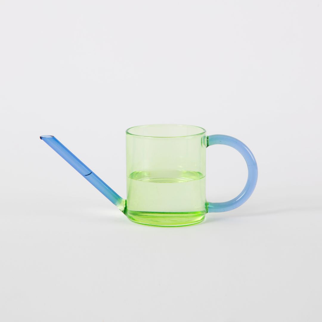 a green glass watering can with a blue handle and spout