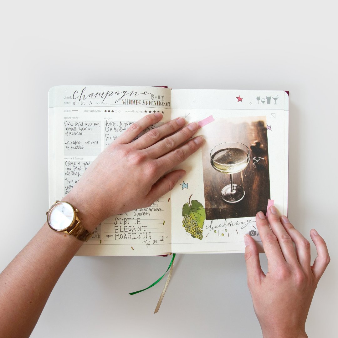 Hand sticking a photo in My Drinks Journal