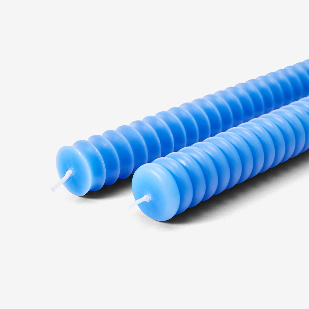 close up of two blue candles - one has convex bumps and the other has concave dips.