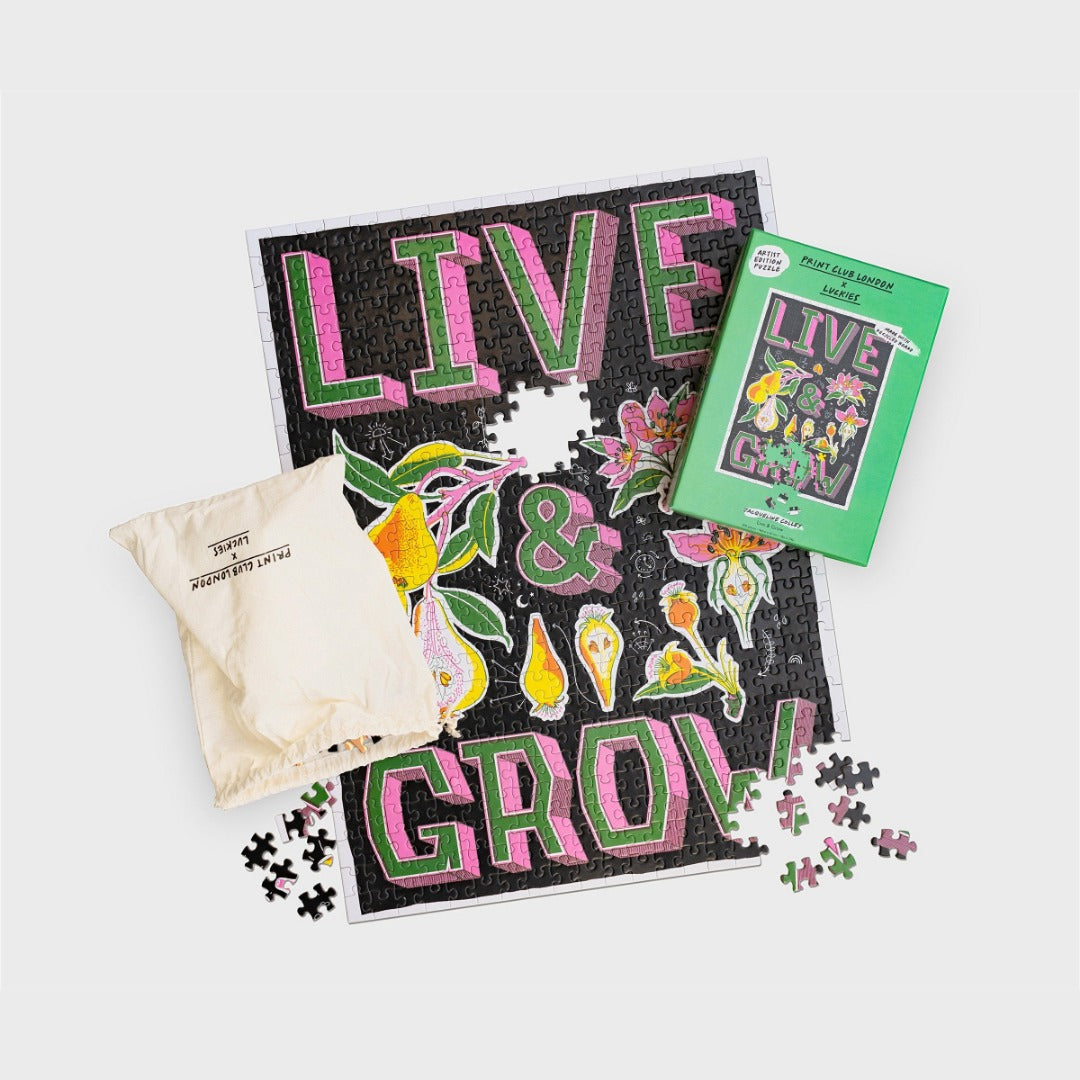 Jigsaw puzzle with words 'Live & Grow' and botanical illustrations. Pictured with box and drawstring bag.