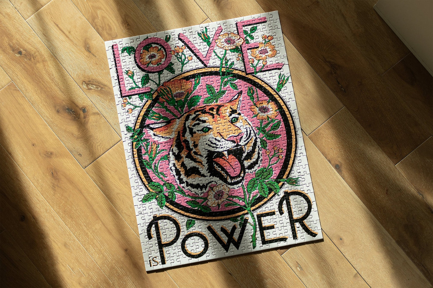 Completed jigsaw puzzle with illustration of a tiger and words 'Love is Power' on a wooden floor.