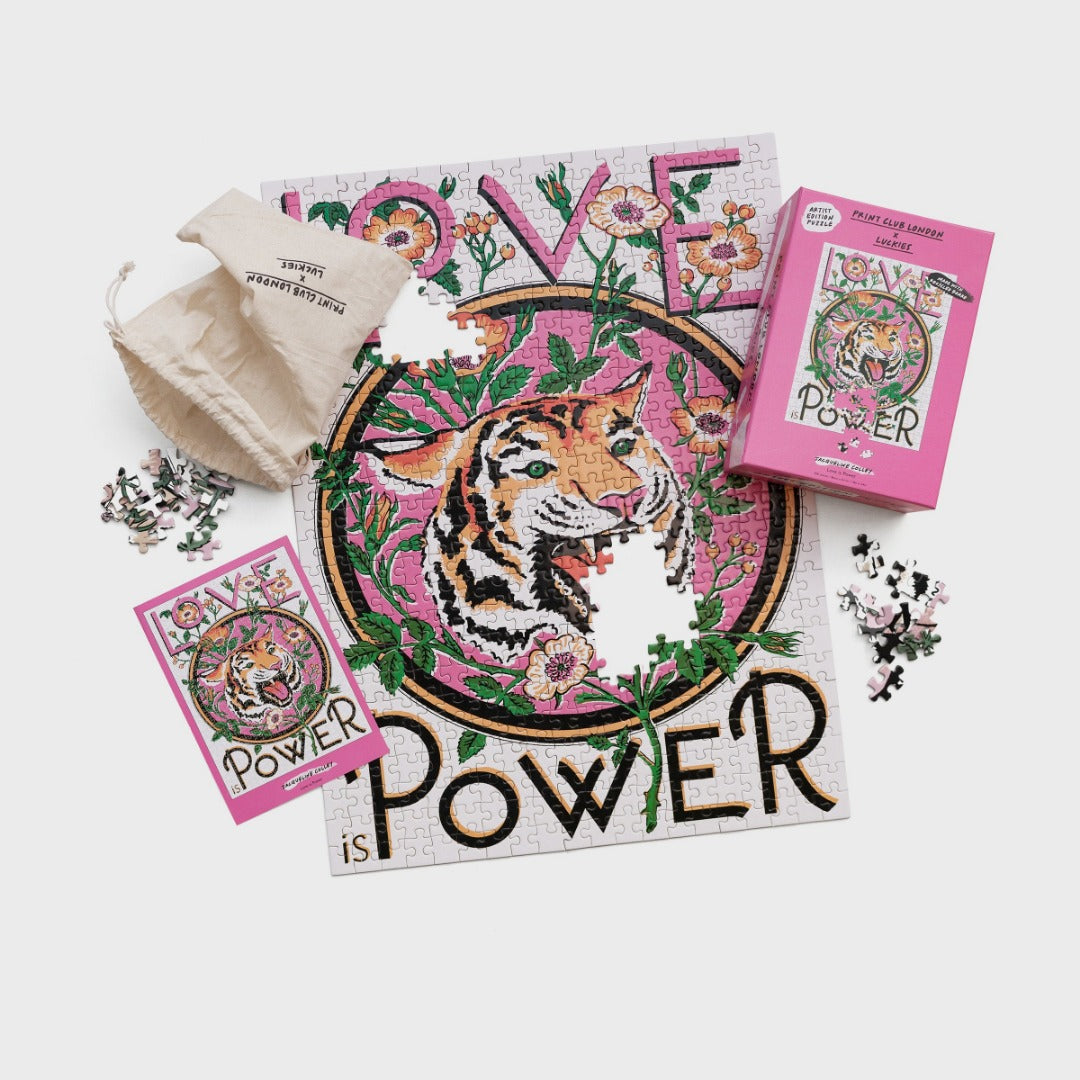 Jigsaw puzzle with illustration of a tiger and words 'Love is Power'. Pictured with box and drawstring bag.