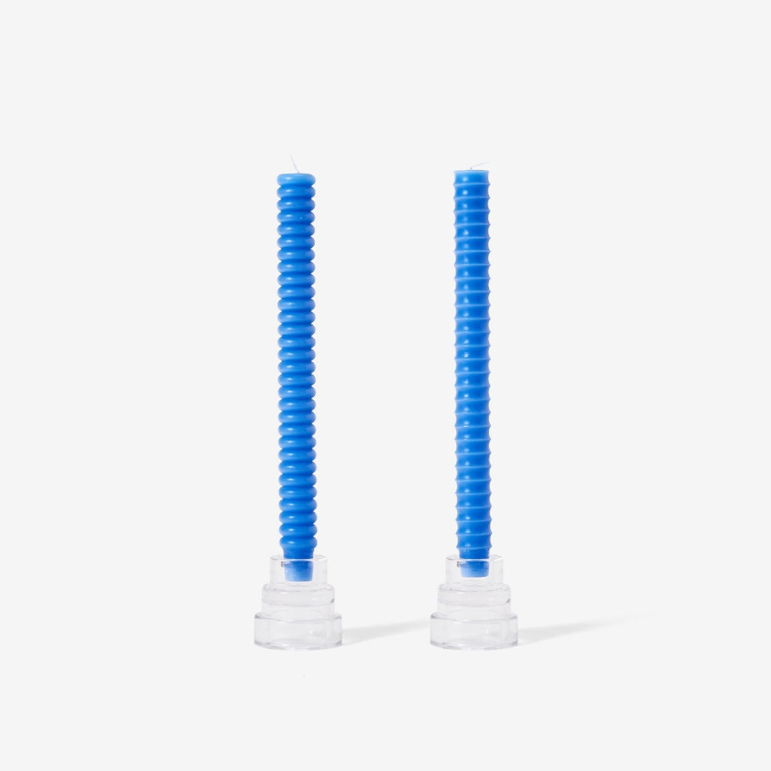 two blue candles in clear stands - one has convex bumps and the other has concave dips.