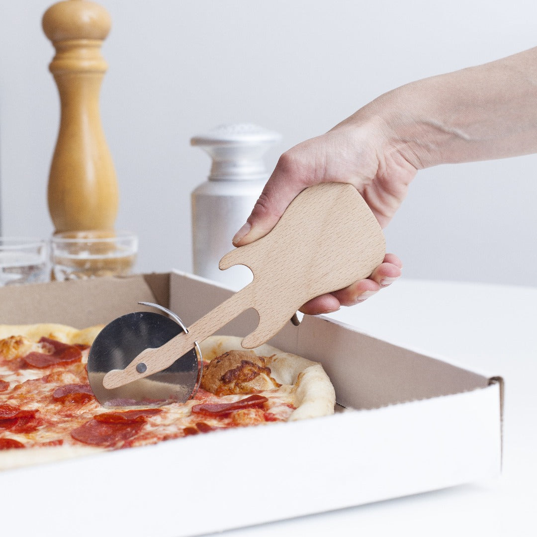 Wooden guitar shaped pizza cutter being used to slice a pepperoni pizza