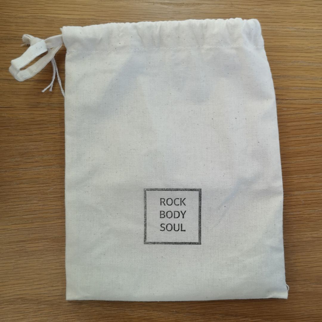 white drawstring bag with 'ROCK BODY SOUL' printed on it in black,