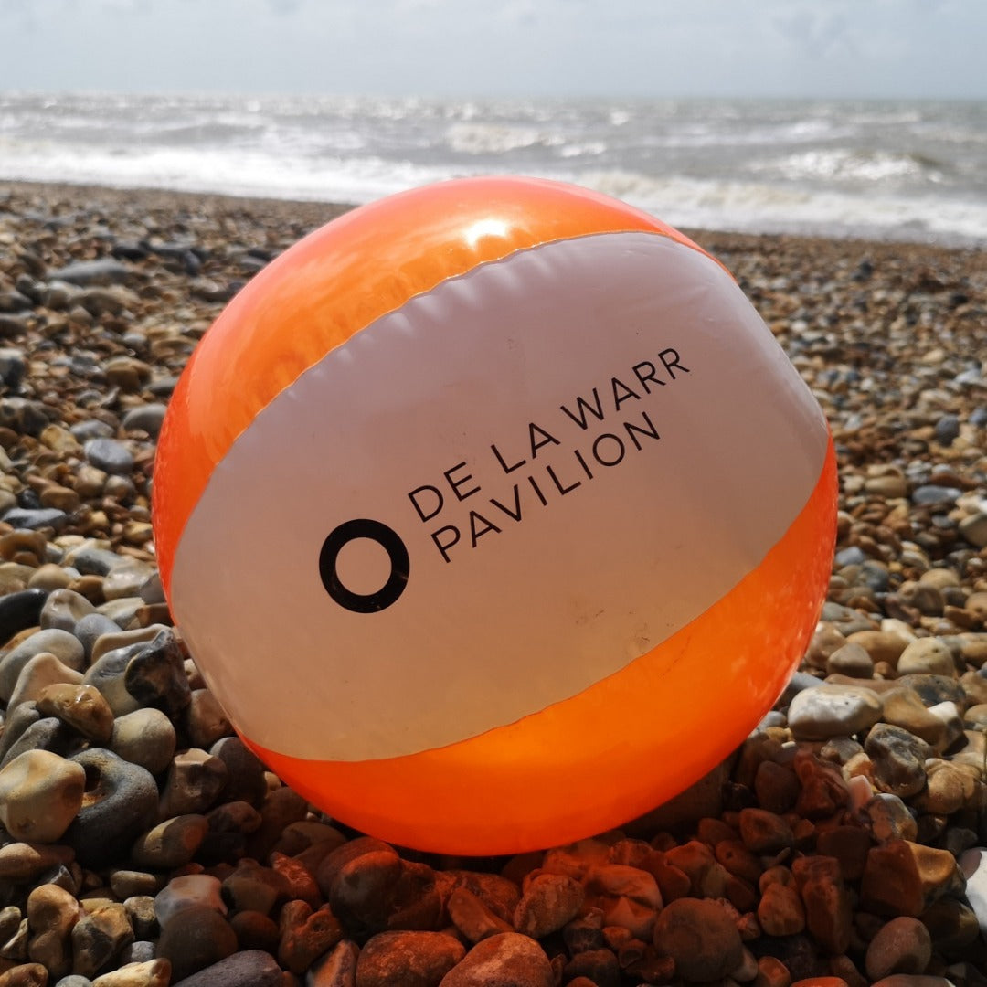 white and orange beach ball featuring De La Warr Pavilion logo on the beach