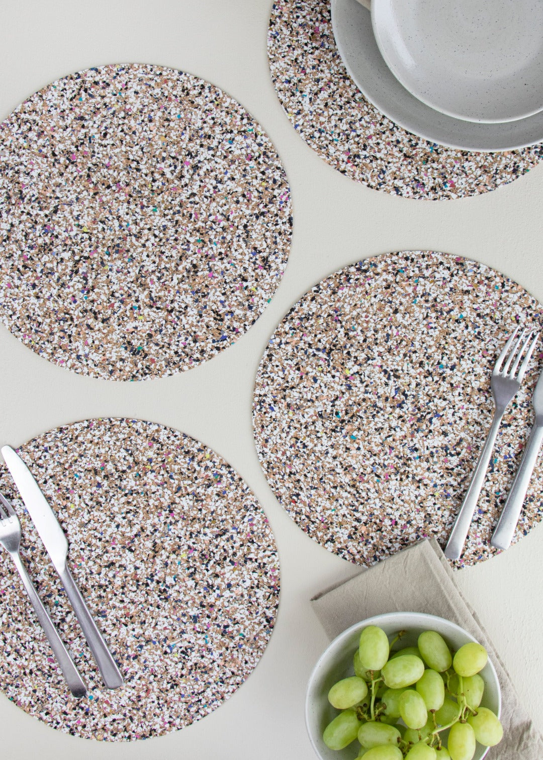 four placemats made from cork and recycled plastic with cutlery and crockery