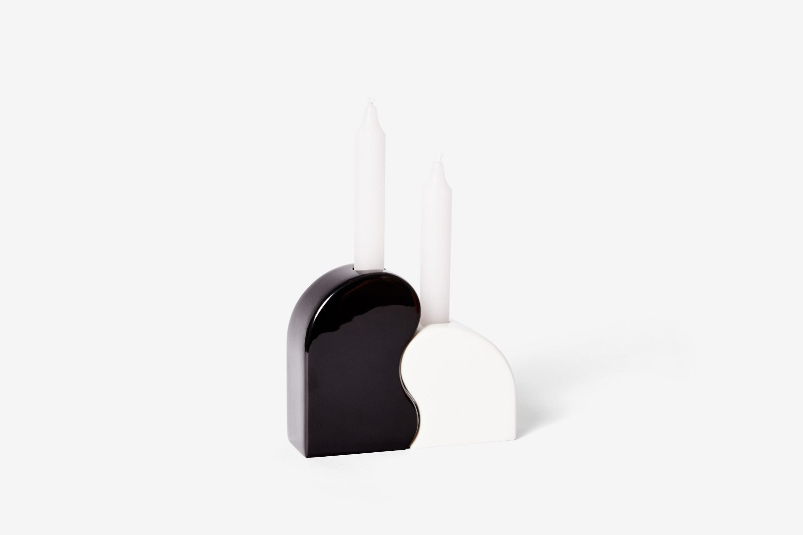 curved black and white candle holders which fit together - two unlit white candles are in them