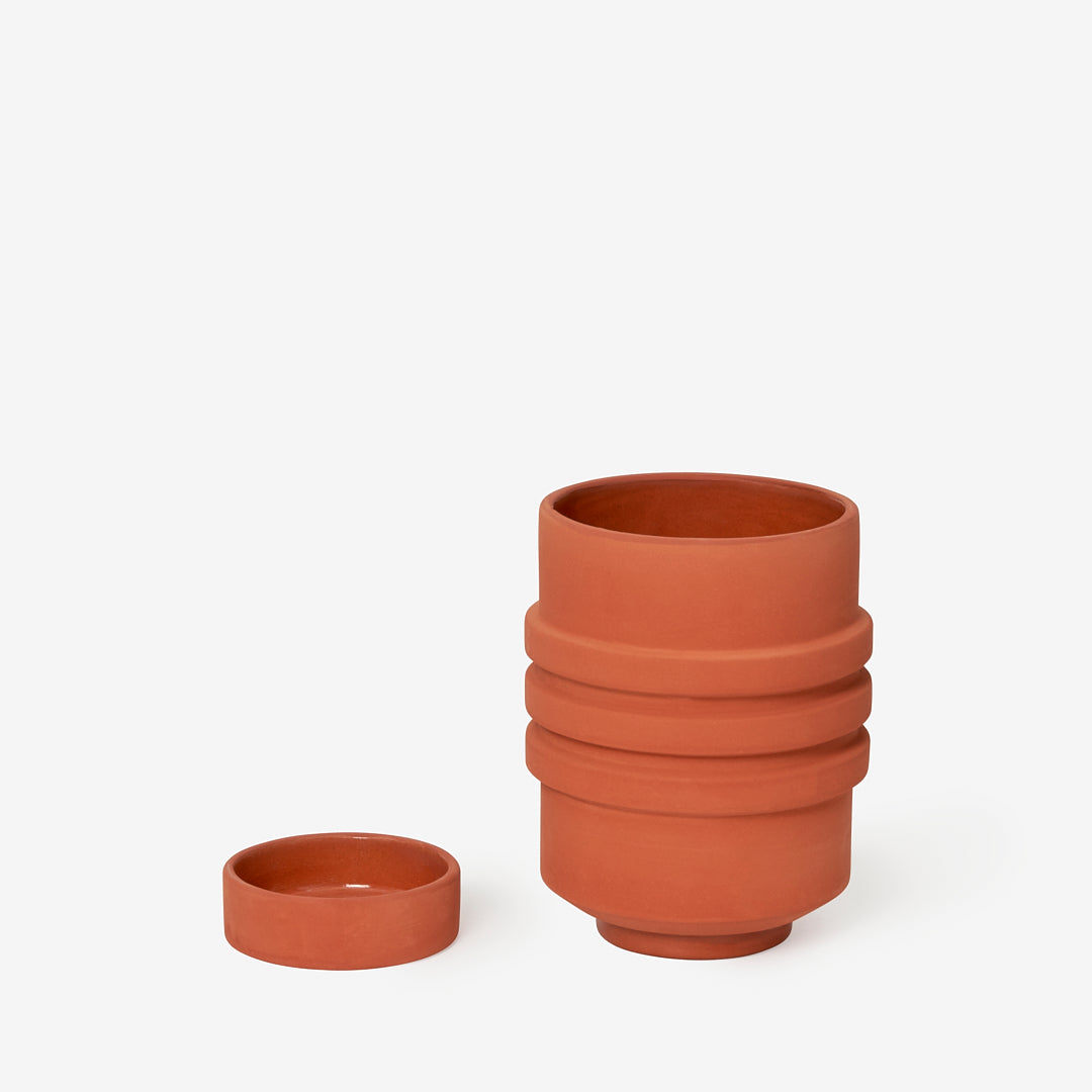 Terracotta plant pot with sculptural ridges and shape, and it's dish/base in the same colour.