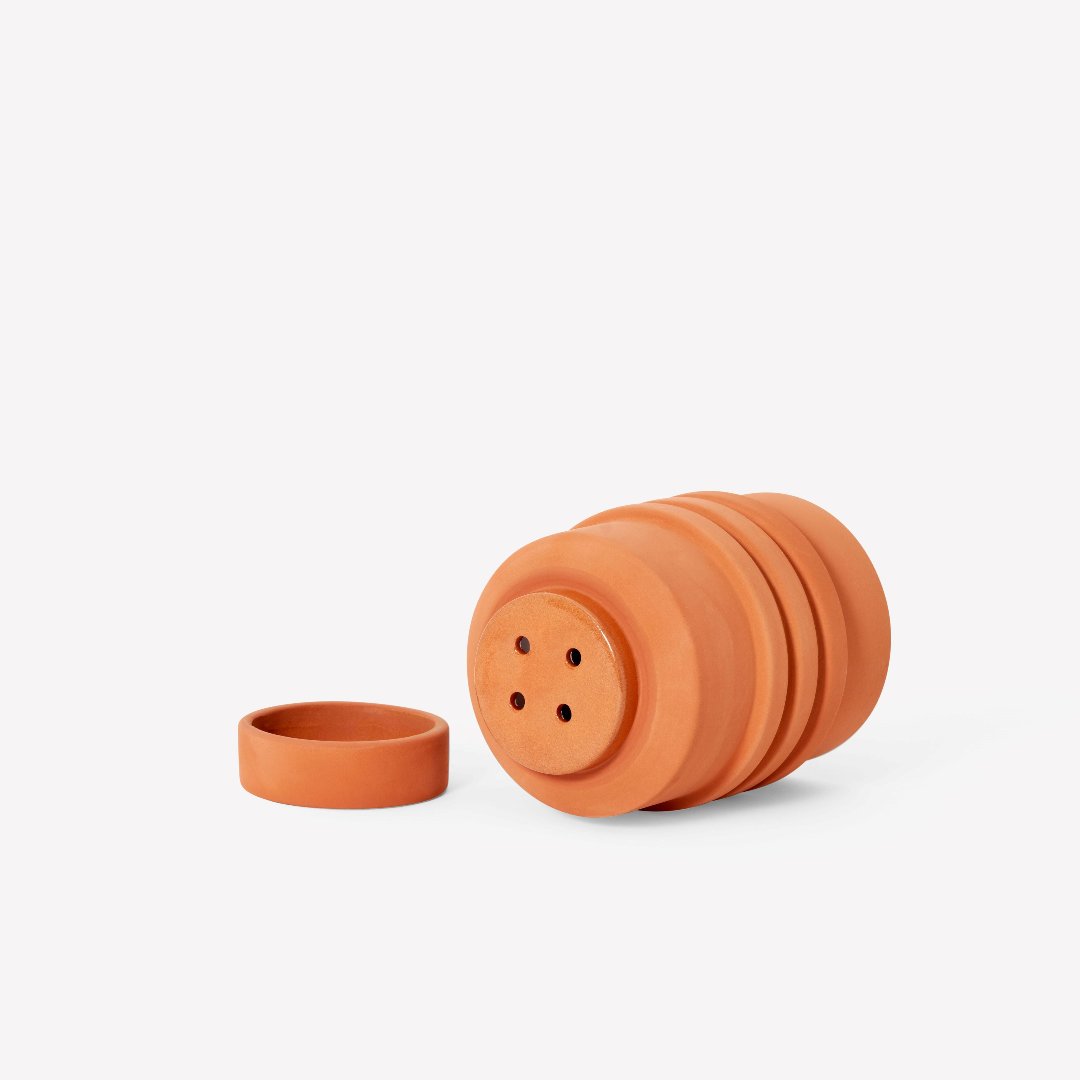 Terracotta plant pot with drainage holes on a terracotta base, and a terracotta base dish.