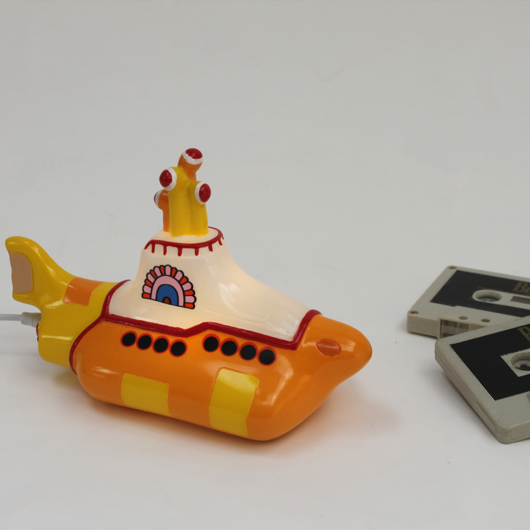 The Beatles Yellow Submarine lamp, plugged in with a white USB cable on a white background